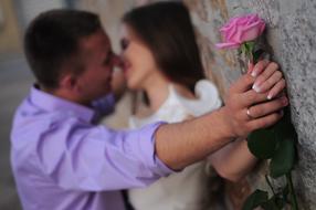 lovers with a rose in hand against the wall