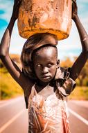 african child Girl standing on road with water in bucket on head