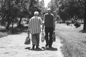 monochrome photo of an elderly couple walking on a country road among the plants