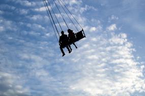 silhouette of a couple on a swing against the blue sky