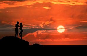 landscape of the couple on a shore at the red sunset