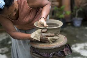 Asian woman makes a clay pot