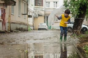 The boy walks through the puddles after the rain