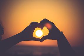 Colorful heart shaped sunset in the hands