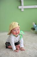 Cute asian Baby in yellow cap sits on carpet