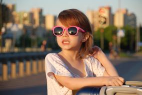 photo of a girl in pink glasses on the embankment