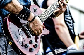 Man playing on the beautiful, red guitar with white hearts on the concert