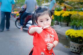 asian Baby girl eating ice cream on street