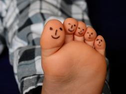 smiling fingers, painting on bare feet of child