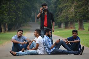 five young dark skin men resting on path in park