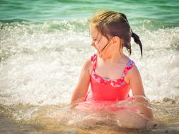 wet girl in a red bathing suit on the seashore