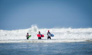 three surfers go to meet the ocean wave