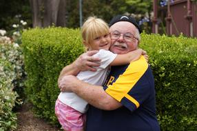 happy Grandfather hugging Granddaughter in garden