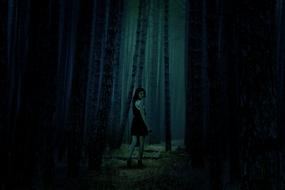 young girl walking away in dark forest