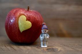 Fruit apple heart and small ceramic fig close-up on blurred background