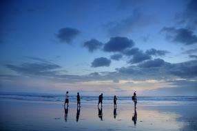 five unrecognizable people on scenic wet Beach at dusk, indonesia, Bali