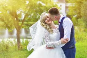 the groom kisses the bride on the lake