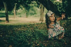 girl in spring dress squatting in the forest