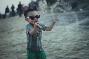 boy throws sand on the beach