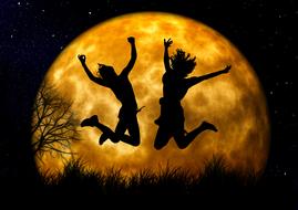 silhouettes of two jumping people on a background of the yellow moon