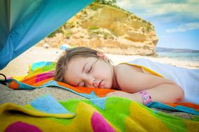 photo of a girl sleeping on the beach by the ocean