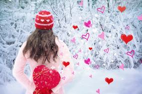 photo of a girl with a plush heart in a winter forest