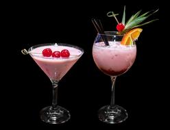 two pink alcoholic cocktails with cherries