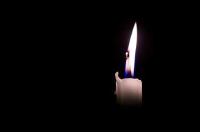 white burning candle in the dark