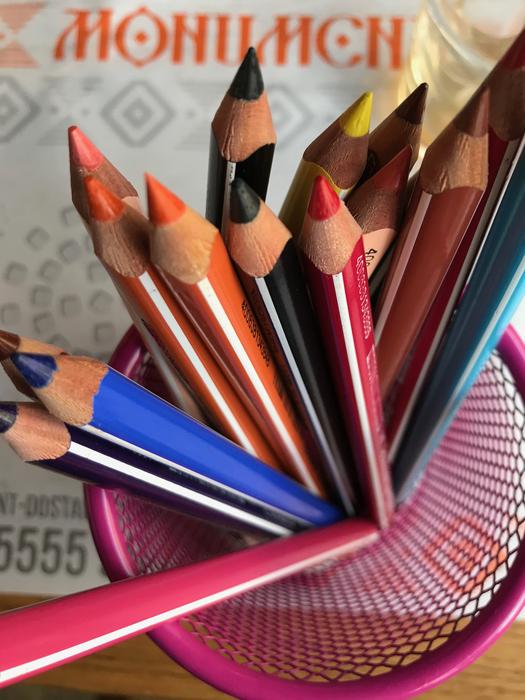 Top view of the colorful, shiny pencils in the folder, near the sign