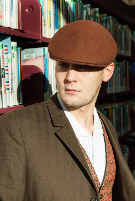 young man in brown cap in the library