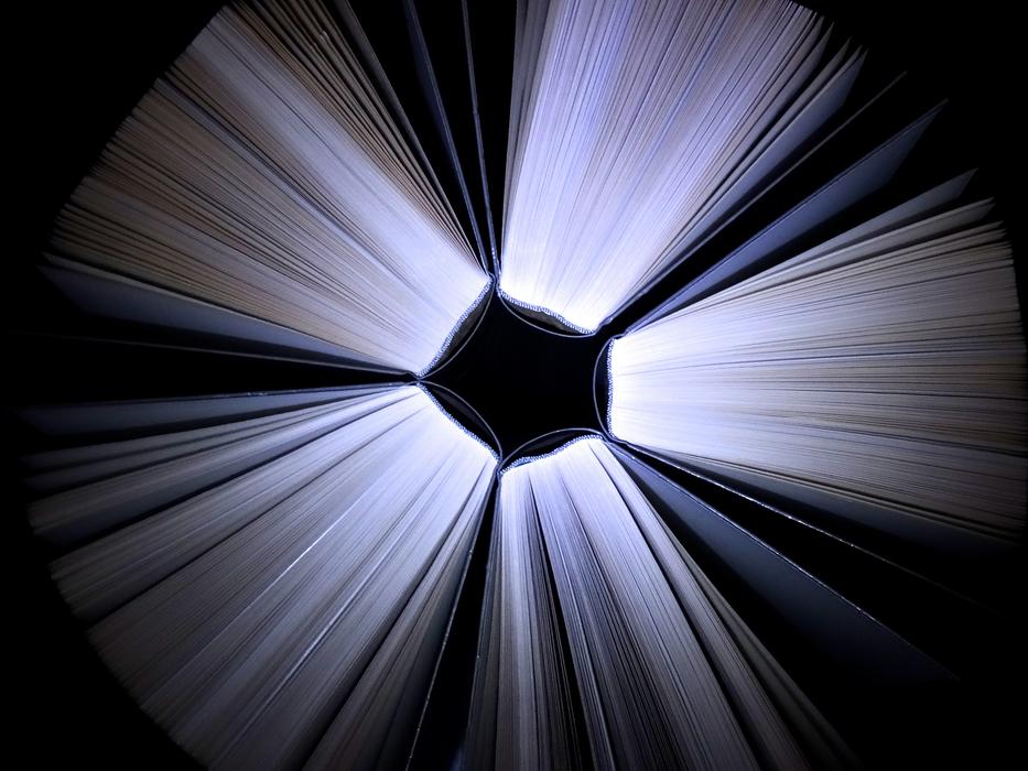 Top view of the shiny books, with the pages in light, among the darkness