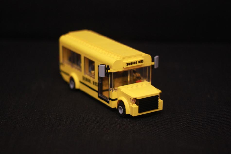 Lego model of the yellow and black school bus, at black background