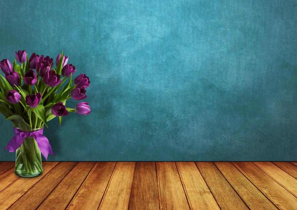 Beautiful bouquet of the purple tulips in the transparent vase, at turquoise background, on the wooden surface