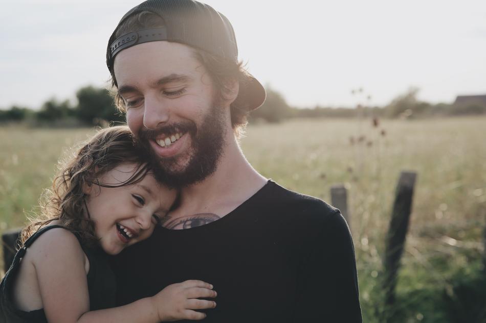 girl on father's hands on the background of agricultural field