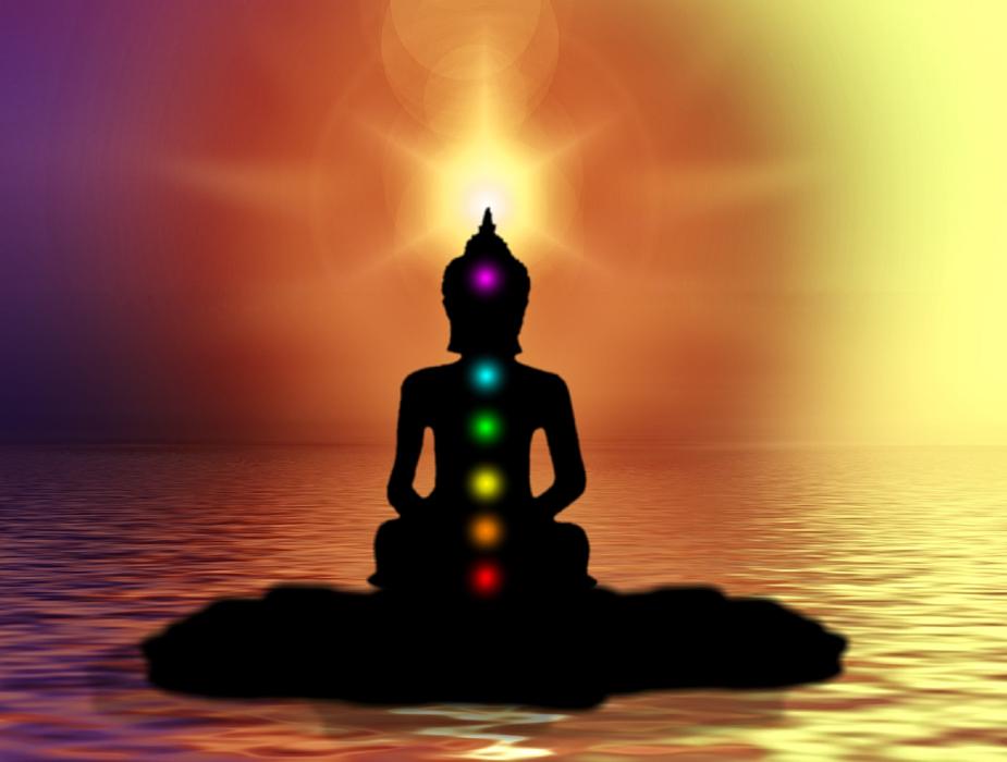 silhouette of buddha with multicolored stones on sunset background