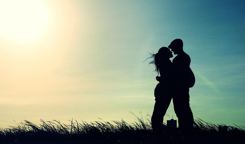 silhouette of a couple in love on the field against the blue sky