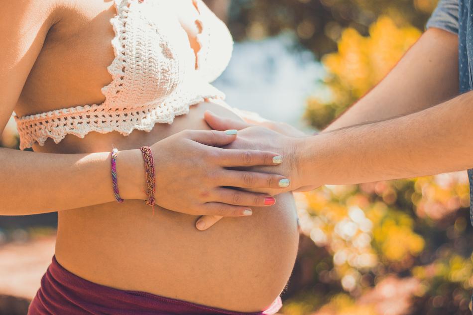 male and female hands on pregnant belly