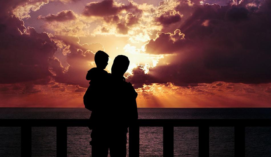 dad with baby stands on the seashore at sunset