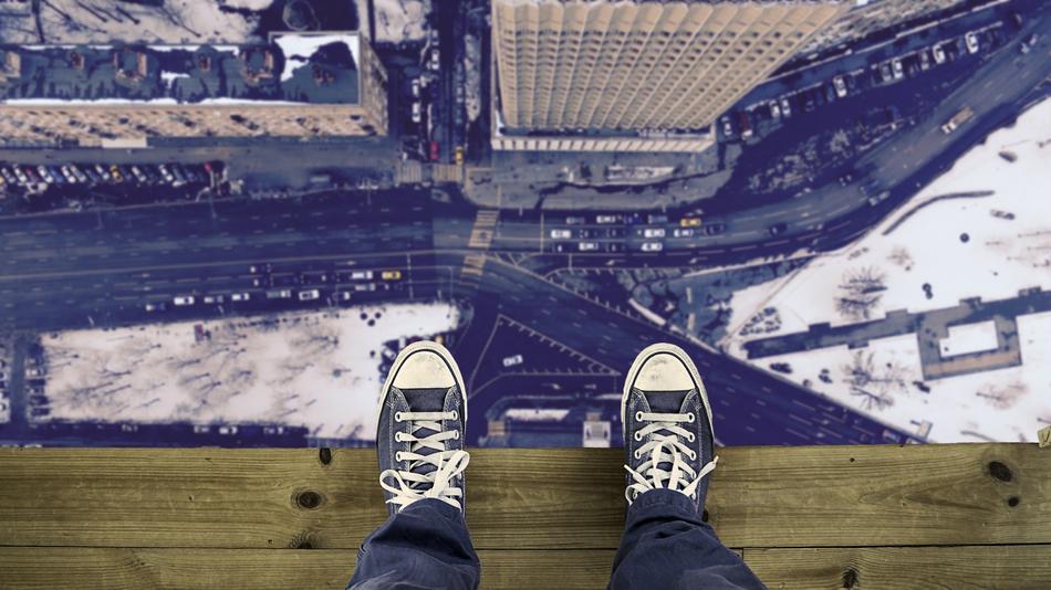 teenager stands on the edge of the roof of a skyscraper