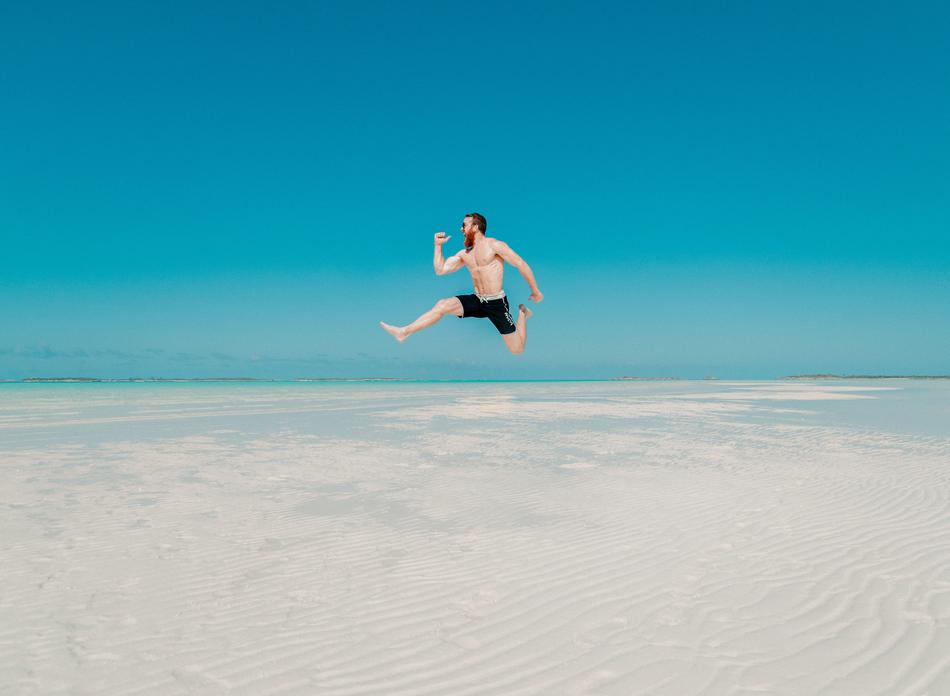 man is jumping on a tropical beach