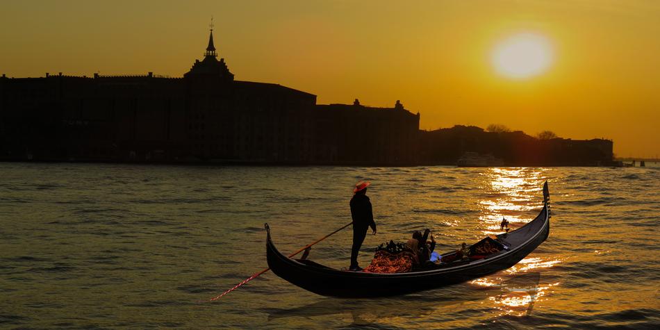 silhouettes of gondolier on the water at dusk