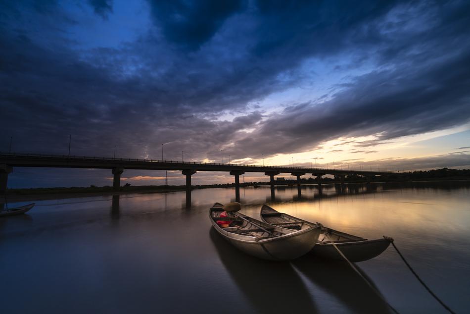 two fishing boats on the background of the bridge in the evening