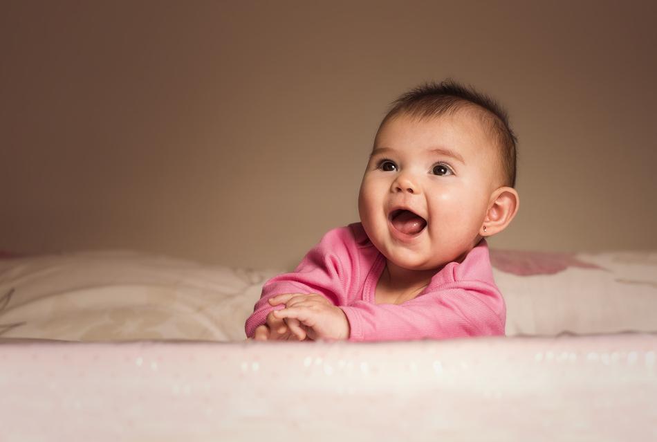 Happy child in pink sweater on the bed