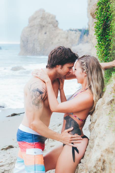 happy Couple, young Boy and Girl kissing at rock on beach