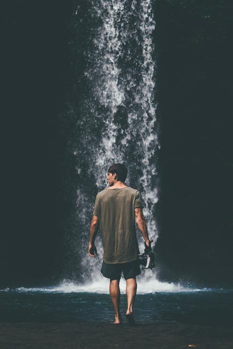 young boy walking to waterfall