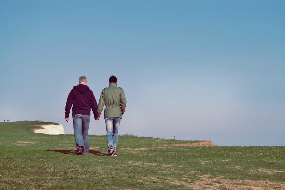 couple holding hands and walking at the top of the cliff