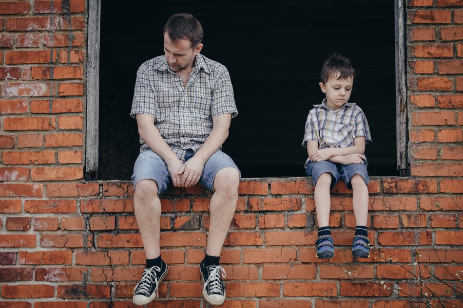 sad father and son are sitting on the windowsill of the brick building