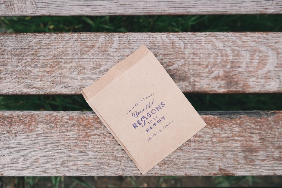 reasons to be happy, stamp on paper bags on Wooden Bench
