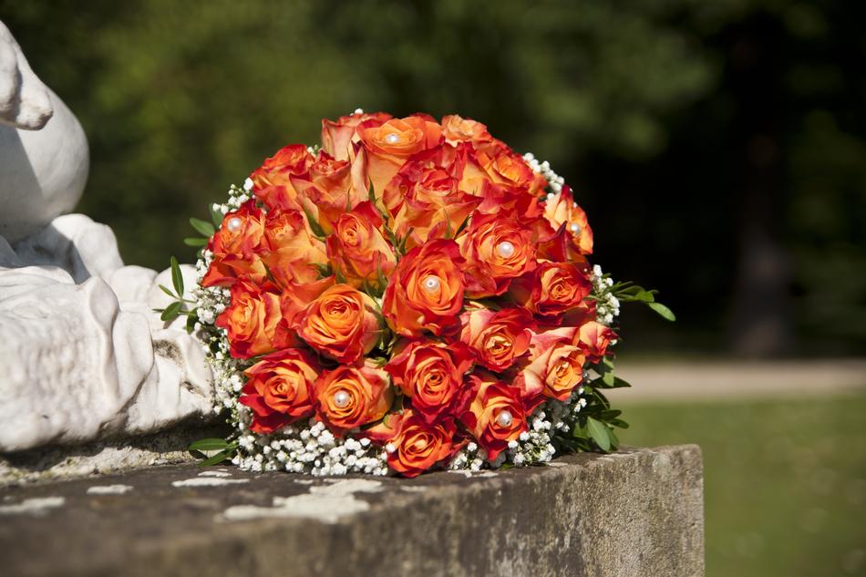 Colorful wedding bouquet lies on a monument at blurred background with plants