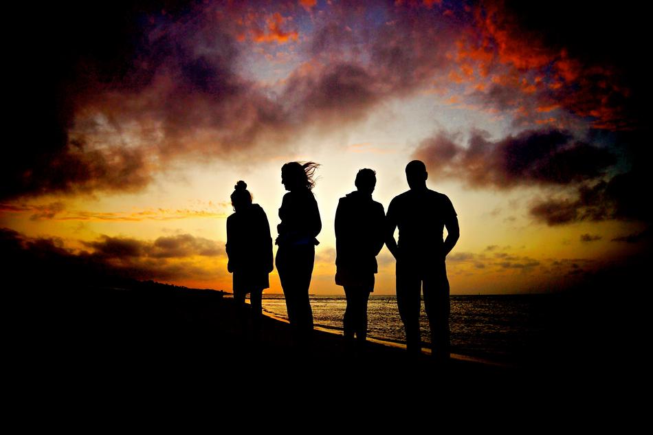 photo of people on the beach against the background of sunset